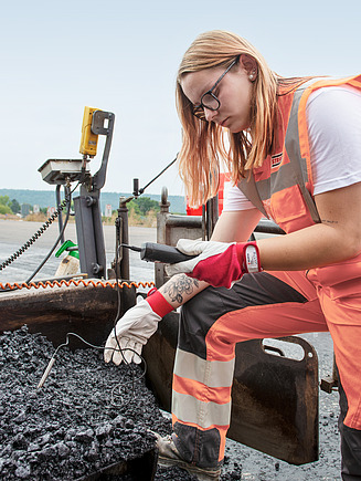 Foto Strassenbauerin misst Temperatur des Asphalts