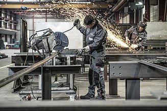 Foto zwei Bauarbeiter beim Bearbeiten von Metall