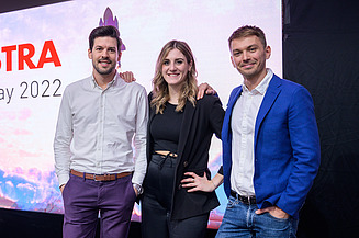 adASTRA Kernteam Franz, Joy-Estelle, Pawel (v.l.) Das adASTRA-Kernteam, bestehend aus Franz, Joy-Estelle und Pawel, stehen auf der einer Bühne