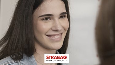 KV-Lernende mit dunklen Haaren und einem strahlendem Lächeln gegenüber einer anderen Person